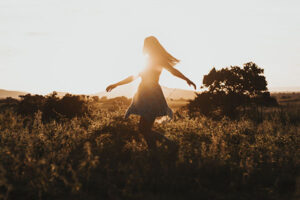 photo of a silhouette of a woman skipping in a field